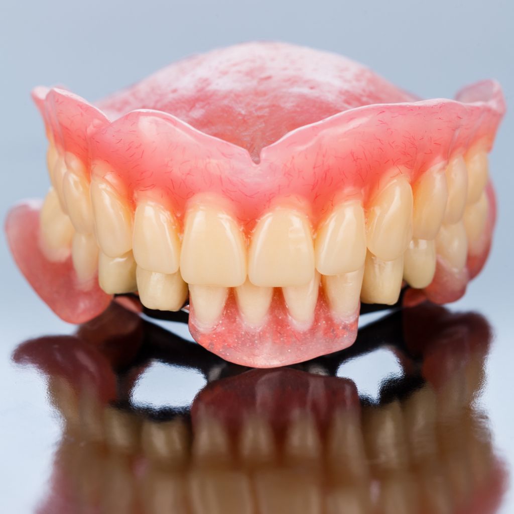 imagem de uma prótese dentária amovível em cima de mesa de vidro