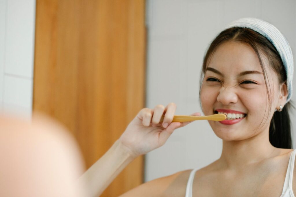 imagem de mulher a escovar os dentes em frente ao espelho